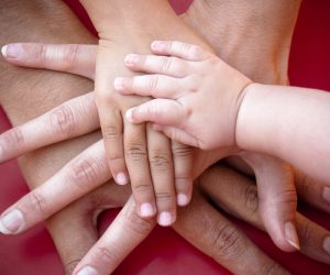 Four hands of the family,  a baby, a daughter,  a mother and a father. Concept of unity, support, protection and happiness.